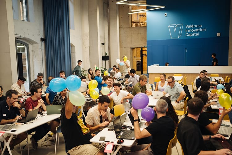 Participants at crowded tables holding up their balloons