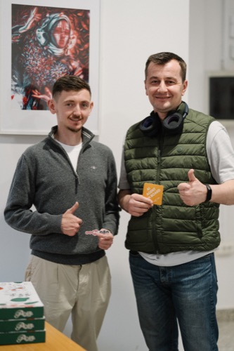 Two attendees holding n8n stickers and giving thumbs up